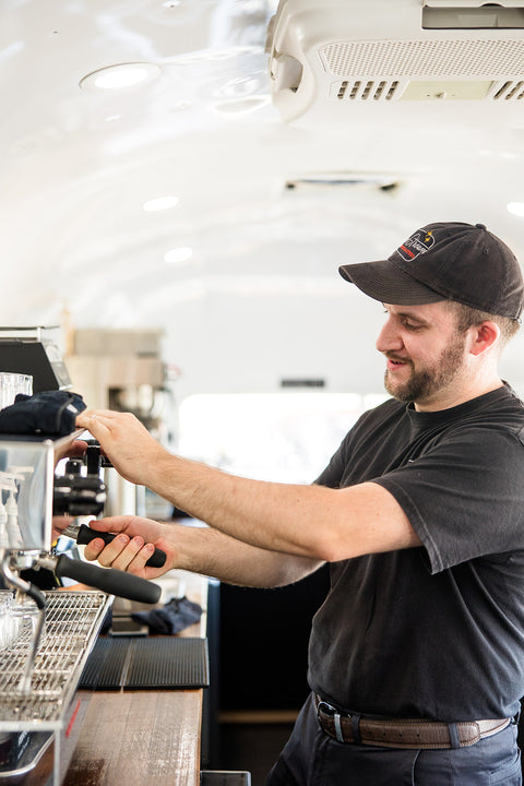 Man operating a coffee machine in a kitchen setting