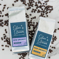 Two packages of Silver Stream Coffee Roasters New Orleans coffee on a marble surface with scattered coffee beans.