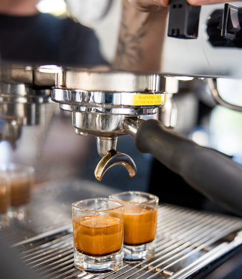 Espresso being extracted from a machine into two small glasses.