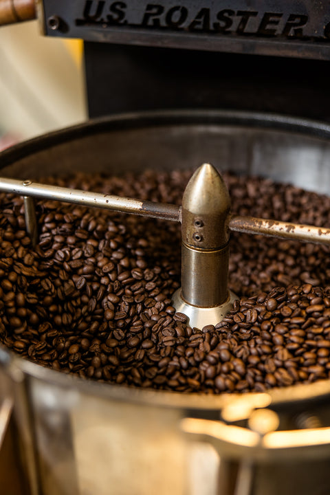 Coffee roasting process with a metal device on top of roasted coffee beans.