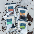 Four packages of silverstream coffee labeled 'Baseline', 'Costa Rican', 'Ethiopian', and 'Sumatran' surrounded by coffee beans on a marble surface.