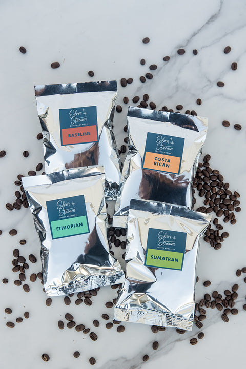 Four packages of silverstream coffee labeled 'Baseline', 'Costa Rican', 'Ethiopian', and 'Sumatran' surrounded by coffee beans on a marble surface.